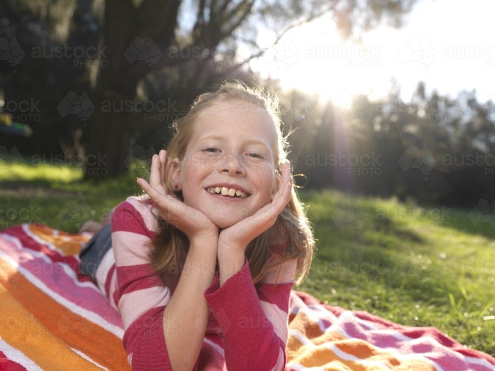 Young girl lying on stripy towel - Australian Stock Image