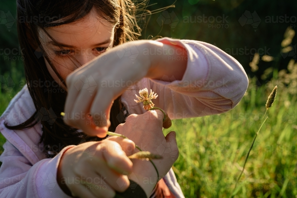 Mum's point of view (POV), daughter dressing her hand with ring & bracelet made from clover flowers - Australian Stock Image