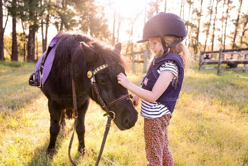 Young girl petting a black horse in a clearing - Australian Stock Image