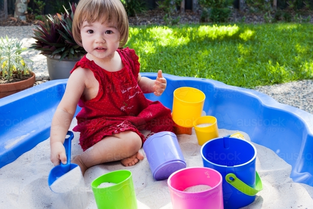 Young girl playing in white sand in backyard - Australian Stock Image