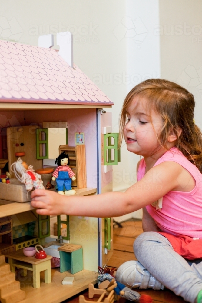 Young girl playing with a dollhouse - Australian Stock Image