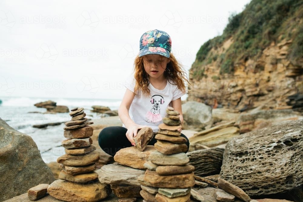 Young girl playing with rocks at the beach - Australian Stock Image