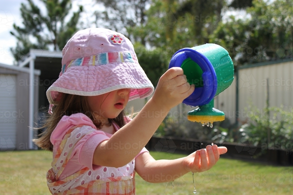 Young girl playing with water in backyard garden - Australian Stock Image