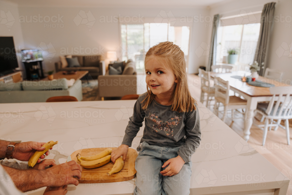 Young girl sitting on the kitchen countertop. - Australian Stock Image