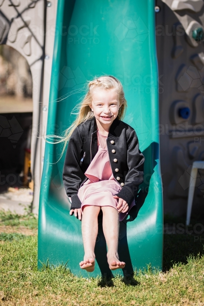 Young girl sliding down slippery dip slide - Australian Stock Image