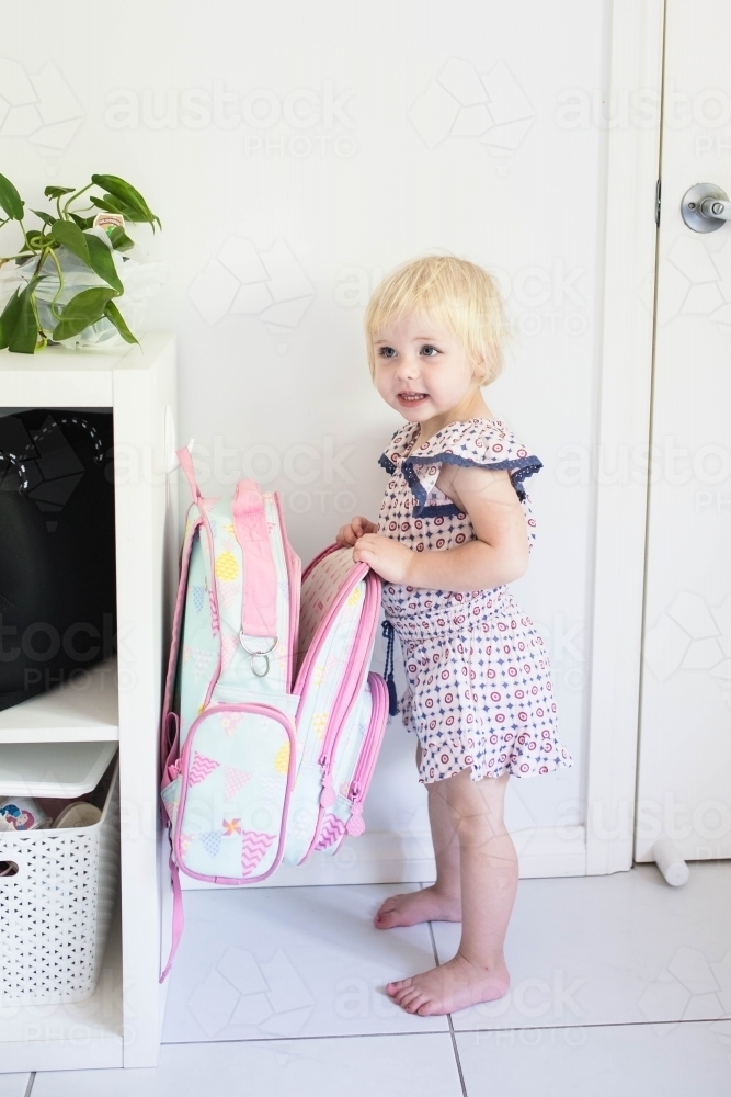 Young girl standing at home with backpack bag smiling - Australian Stock Image