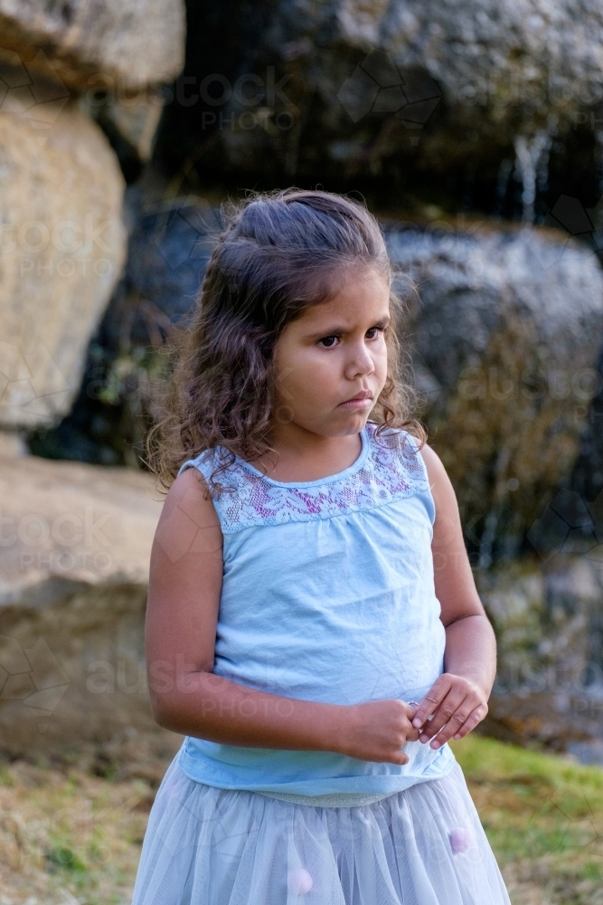 Young girl standing on a flat rock by small waterfall - Australian Stock Image