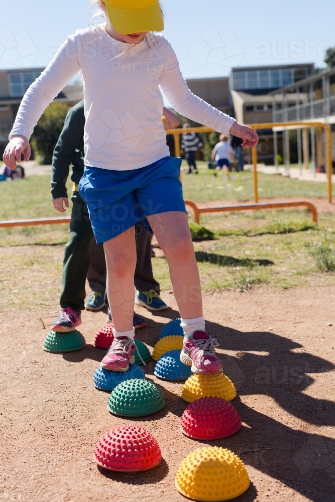 Young girl stepping on colourful stepping stones - Australian Stock Image