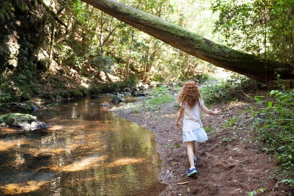 Young girl walking alongside a creek - Australian Stock Image