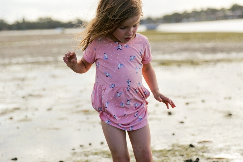 Young girl wandering along and exploring the edge of the ocean - Australian Stock Image