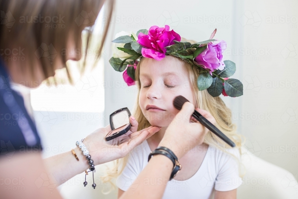 Young girl wearing flower crown getting makeup done - Australian Stock Image