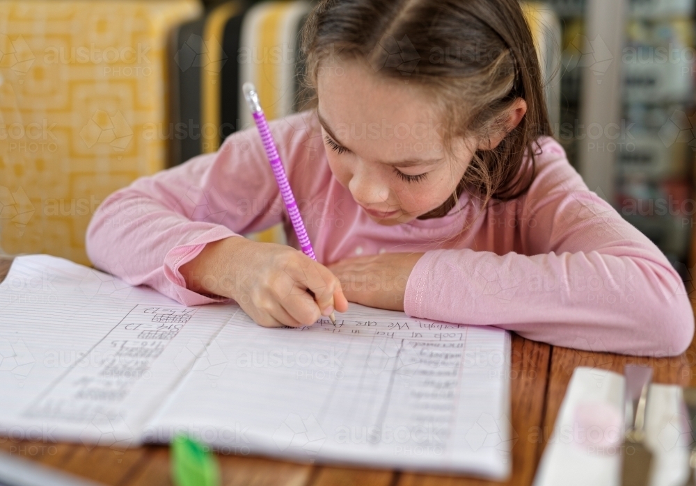 Young girl working on a task in her homework book - Australian Stock Image