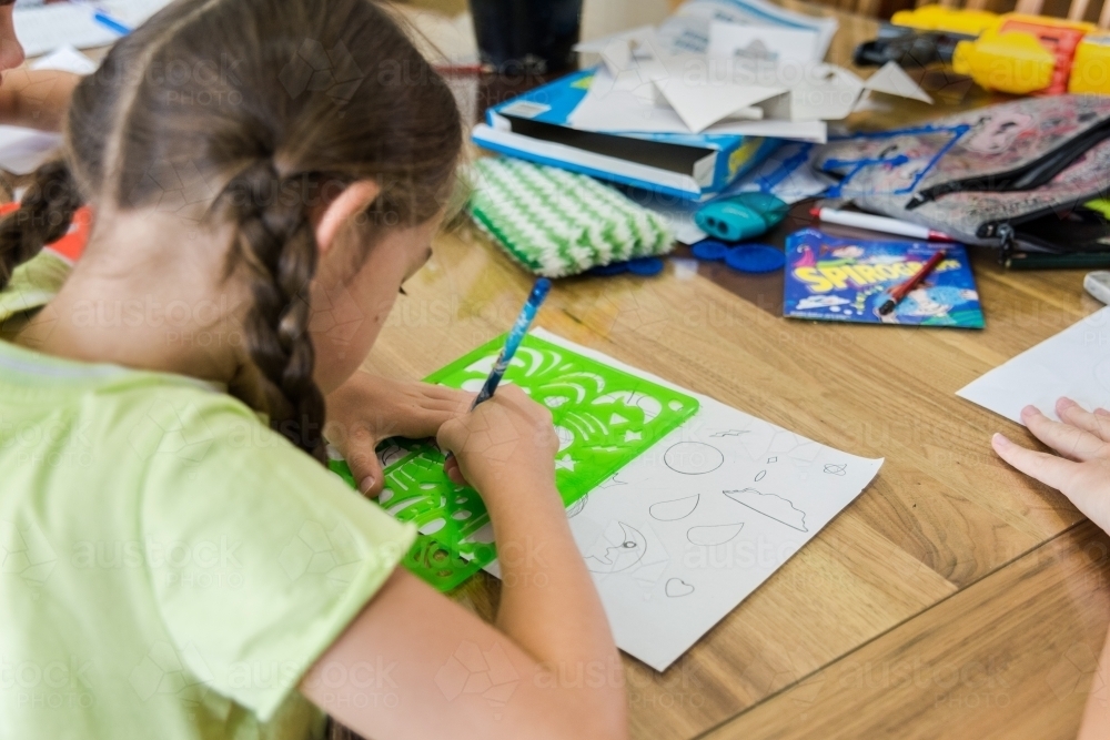 Young girls are creating artwork, drawing Manga and stencilling at the table - Australian Stock Image