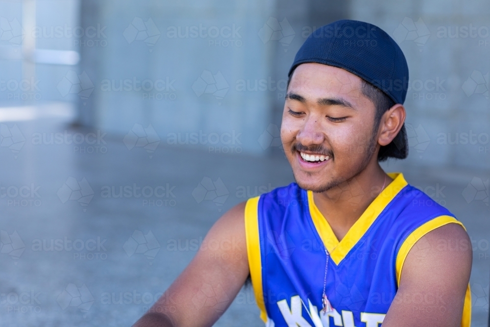 young guy sitting with baseball cap on backwards - Australian Stock Image