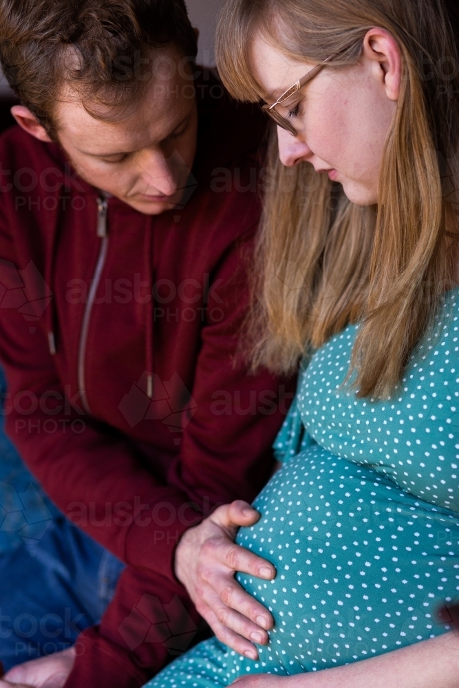 Young husband touching wife's pregnant belly - lifestyle maternity - Australian Stock Image