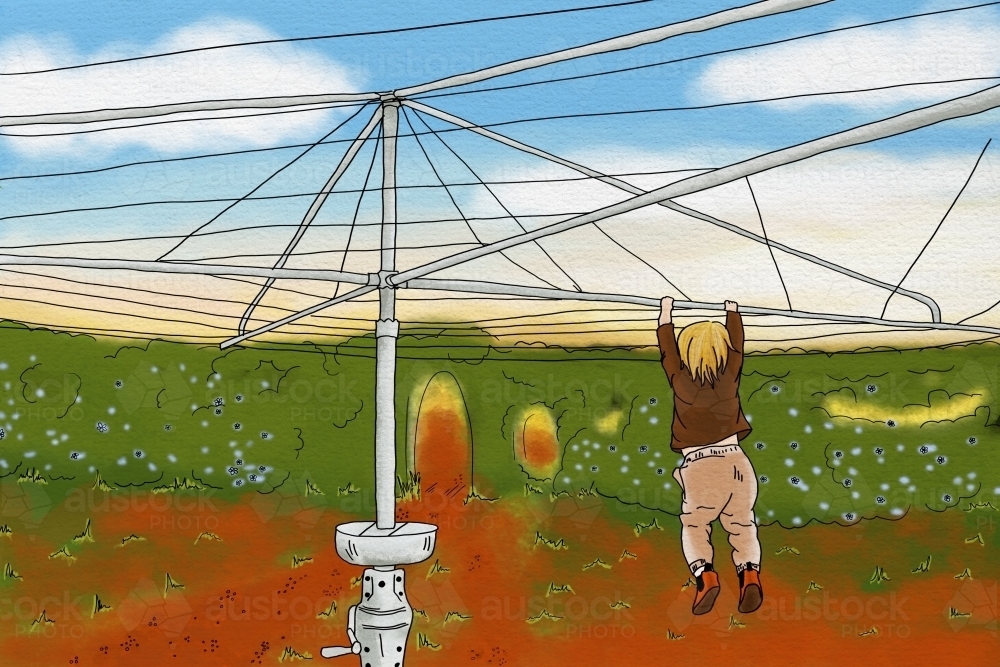 Young kid hanging on hills hoist washing line in Aussie backyard with red dirt - Australian Stock Image