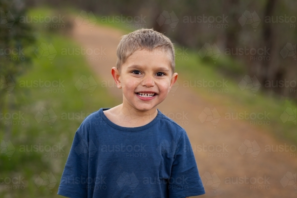 young kid outdoors smiling and looking at camera - Australian Stock Image