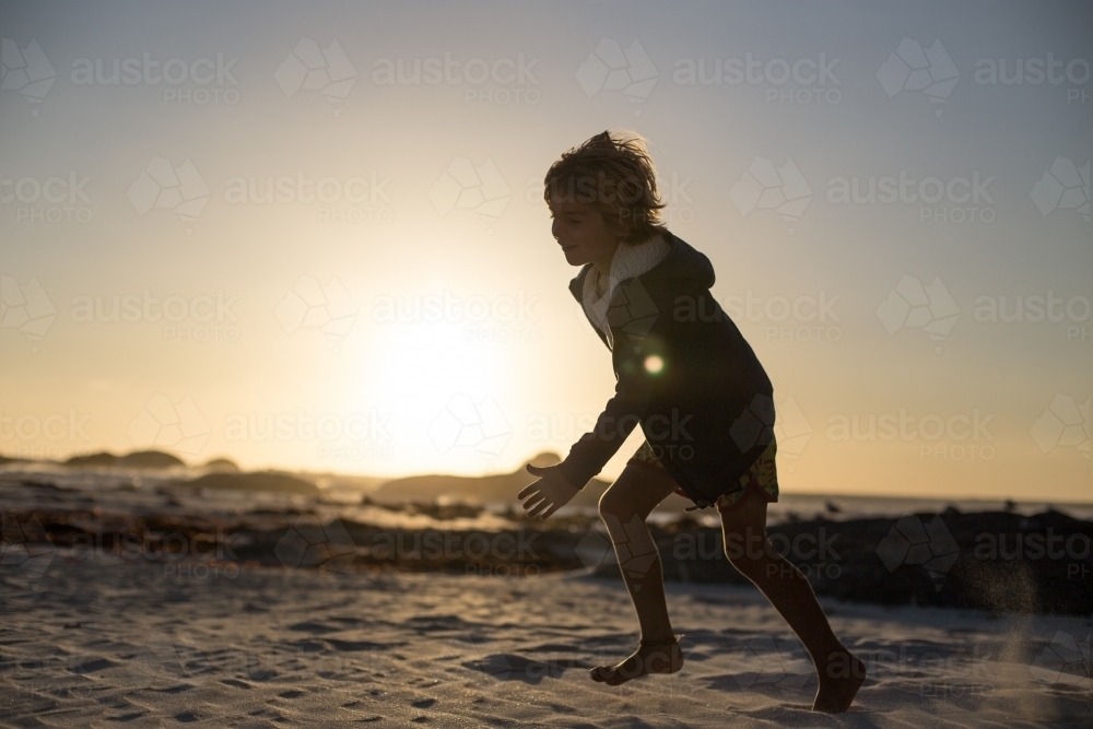 Young kid playing on sunset beach - Australian Stock Image