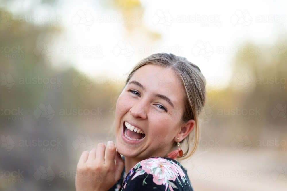 young lady looking over  shoulder and laughing - Australian Stock Image