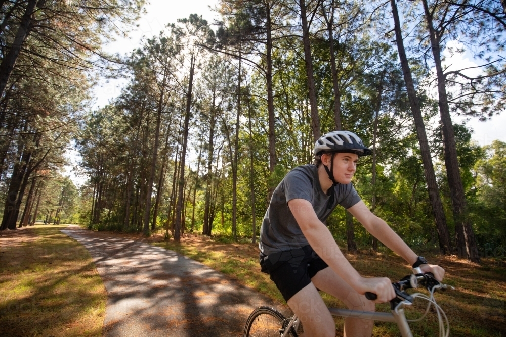 Young male cycling along a parkland bike path - Australian Stock Image