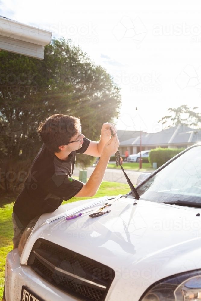 Young man fixing his cars windscreen wipers - Australian Stock Image