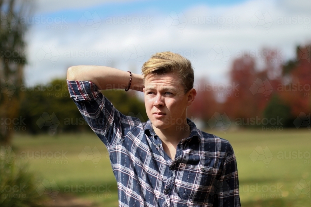 Young man in a flannel scratching his head with a concerned expression - Australian Stock Image