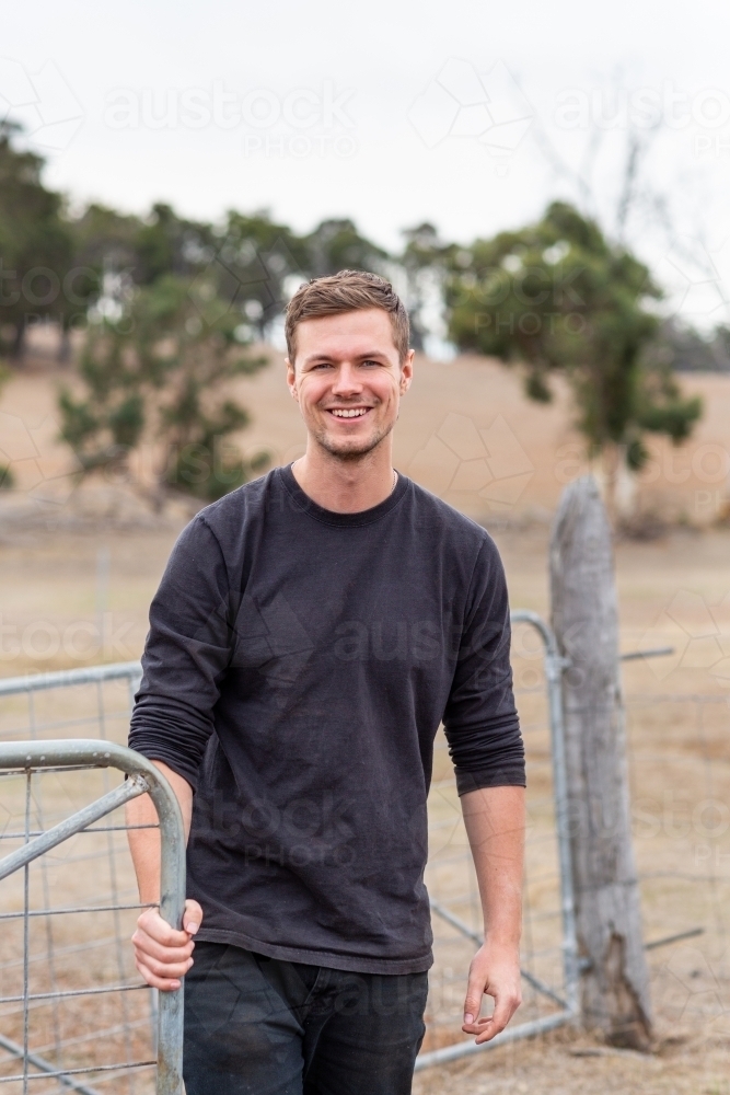 Young man opening a gate on a country property - Australian Stock Image