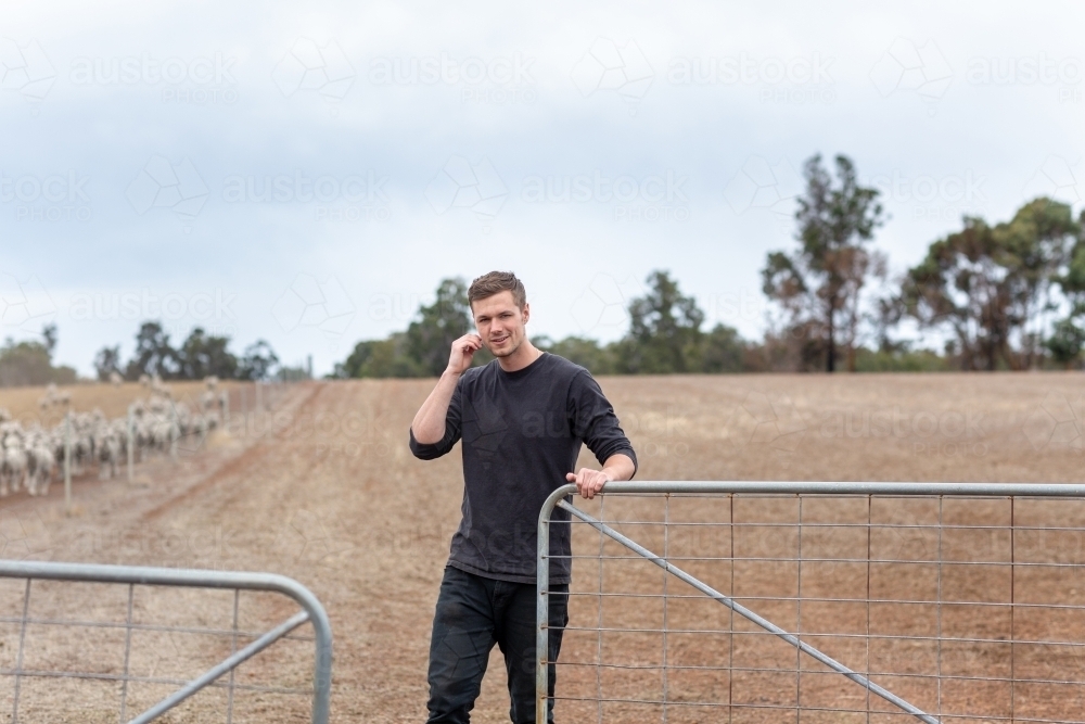 Young man opening gate on country property - Australian Stock Image