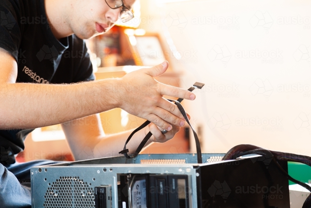 Young man pulling apart and re-building home computer - Australian Stock Image