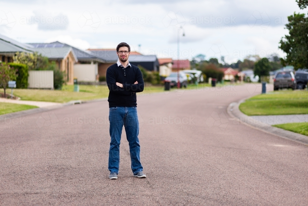 Young man with arms folded standing on road - Australian Stock Image