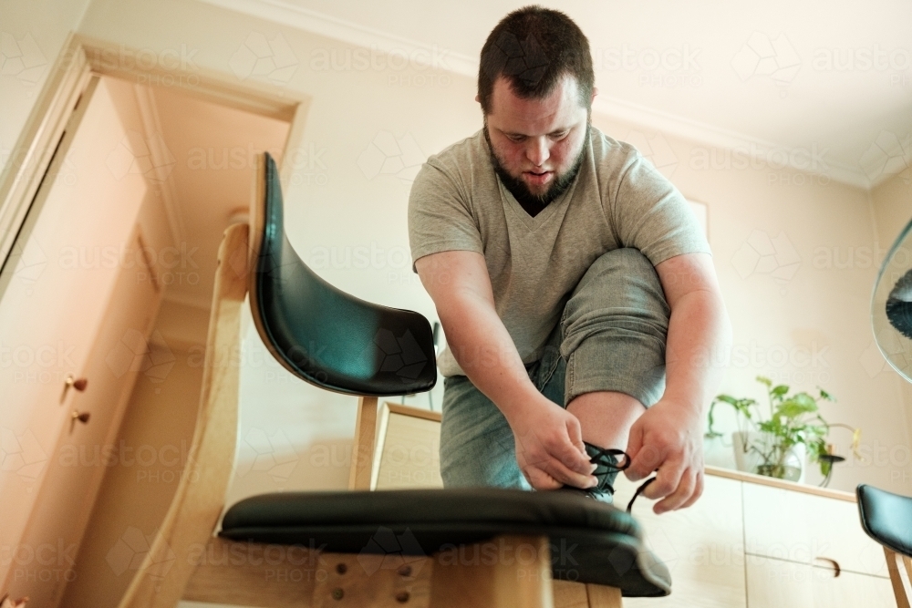 Young Man with Down Syndrome Doing Up Laces - Australian Stock Image