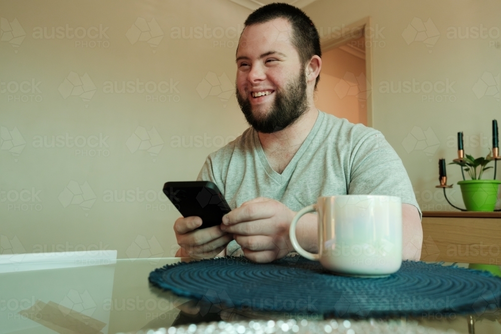 young-man-with-down-syndrome-laughing-and-holding-smartphone-austockphoto-000224874.jpg