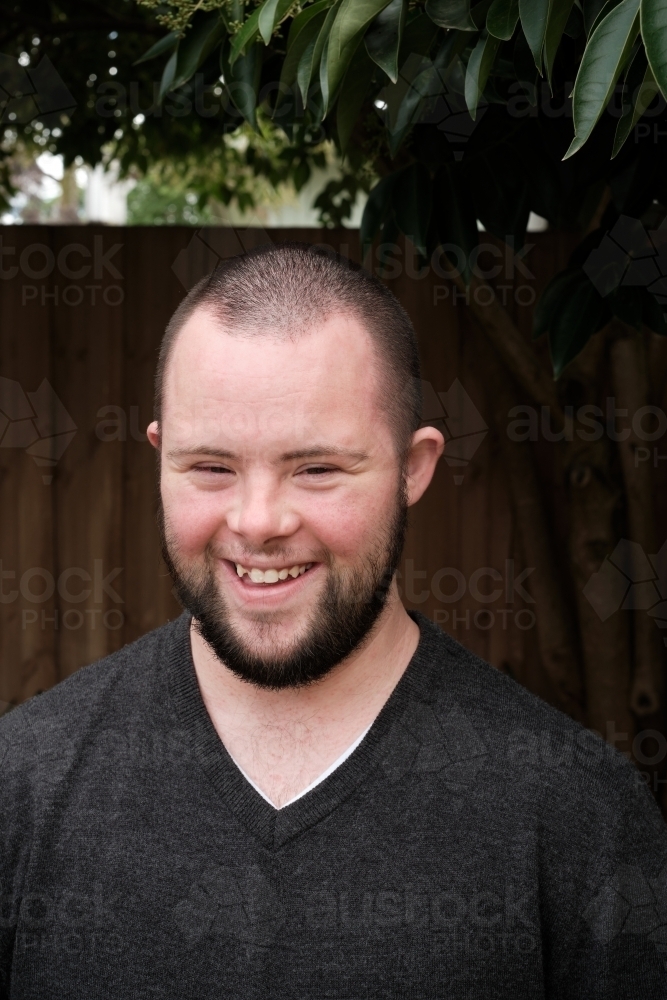 Young Man with Down Syndrome Smiling in Backyard - Australian Stock Image