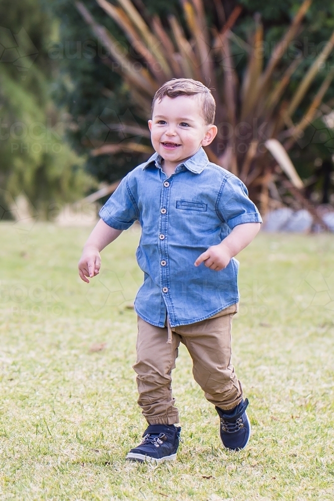 Young mixed race aboriginal caucasian boy running in garden smiling - Australian Stock Image