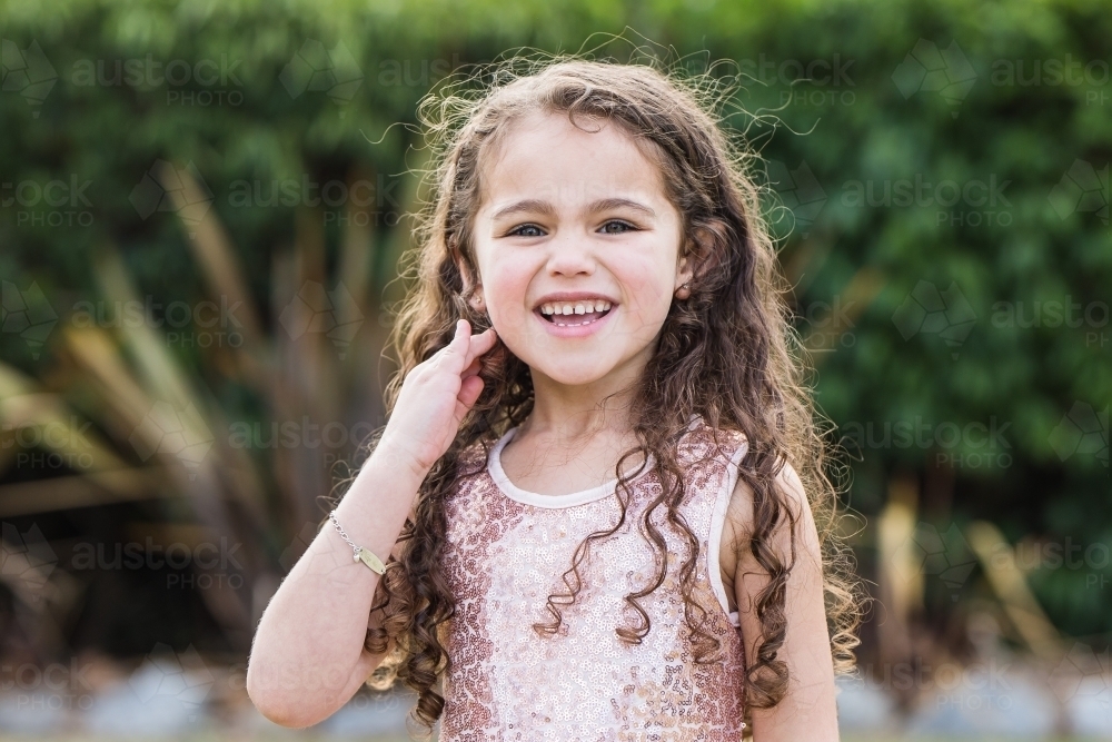 Young mixed race aboriginal caucasian girl laughing brushing hair from face - Australian Stock Image