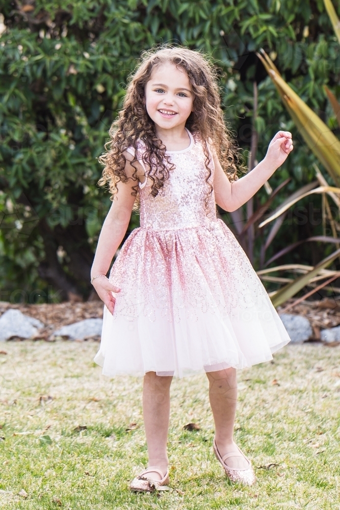 Young mixed race aboriginal caucasian girl with curly hair standing in garden smiling - Australian Stock Image