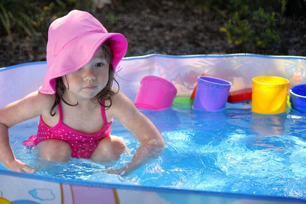 Young mixed race girl playing in a small pool in Australian backyard - Australian Stock Image