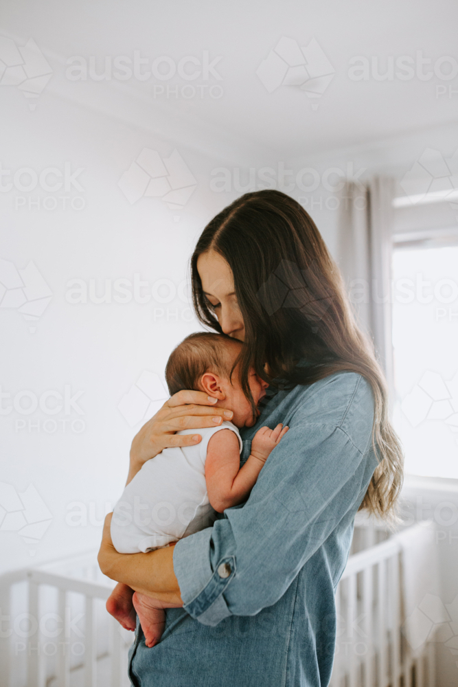 Young mother carrying newborn baby boy in the room - Australian Stock Image