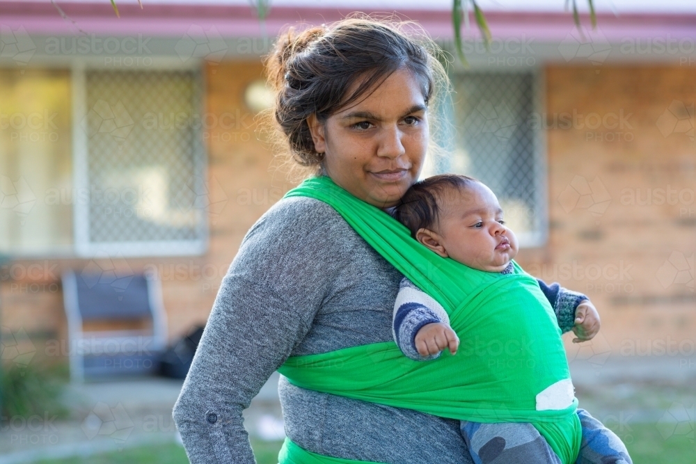 Young mother wearing her baby in a green wrap - Australian Stock Image