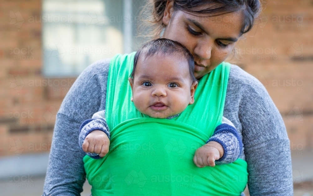 Young mother wearing her baby in a wrap - Australian Stock Image