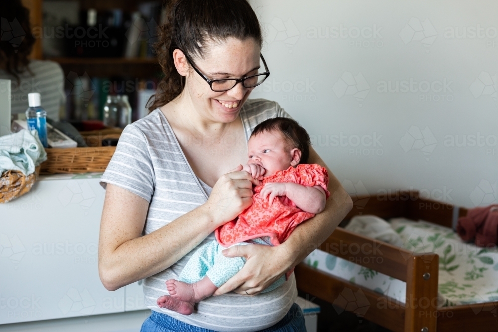 Young mummy holding newborn baby safe in her arms - Australian Stock Image