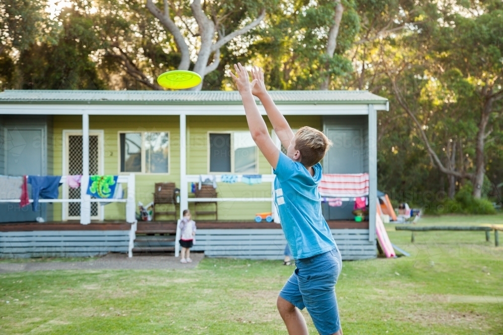 Young person jumping to catch a frisbee - Australian Stock Image