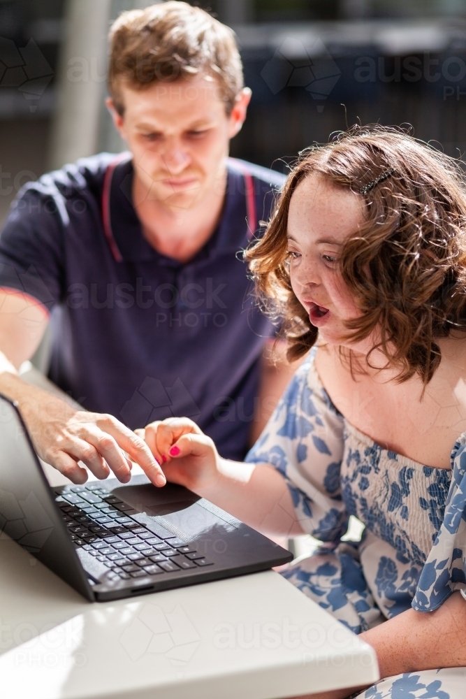 Young person who has down syndrome working with her disability worker NDIS provider on laptop - Australian Stock Image