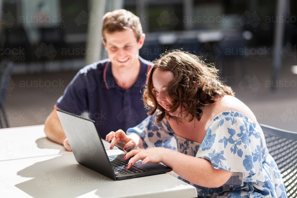 Young person who has down syndrome working with her disability worker NDIS provider on laptop - Australian Stock Image