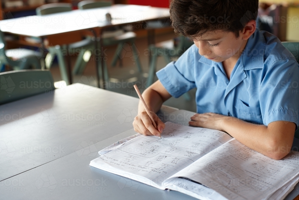 Young school boy doing maths in class - Australian Stock Image