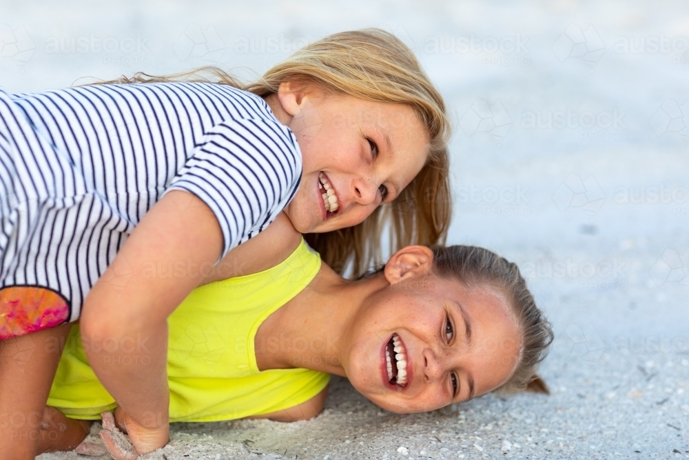 young siblings wrestling and laughing on the ground - Australian Stock Image