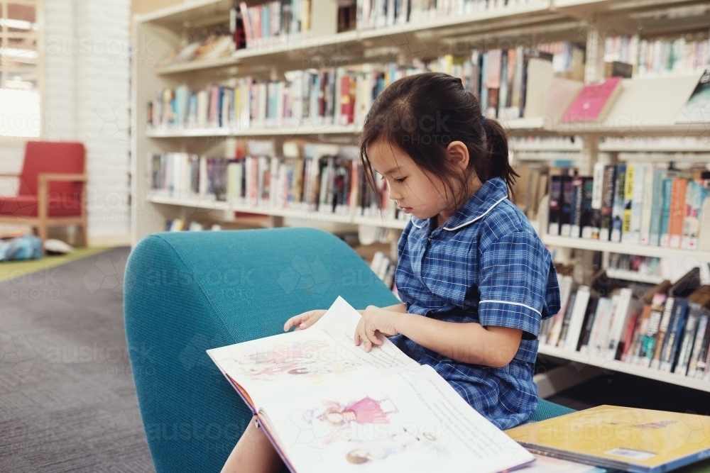 Young student girl reading in library - Australian Stock Image