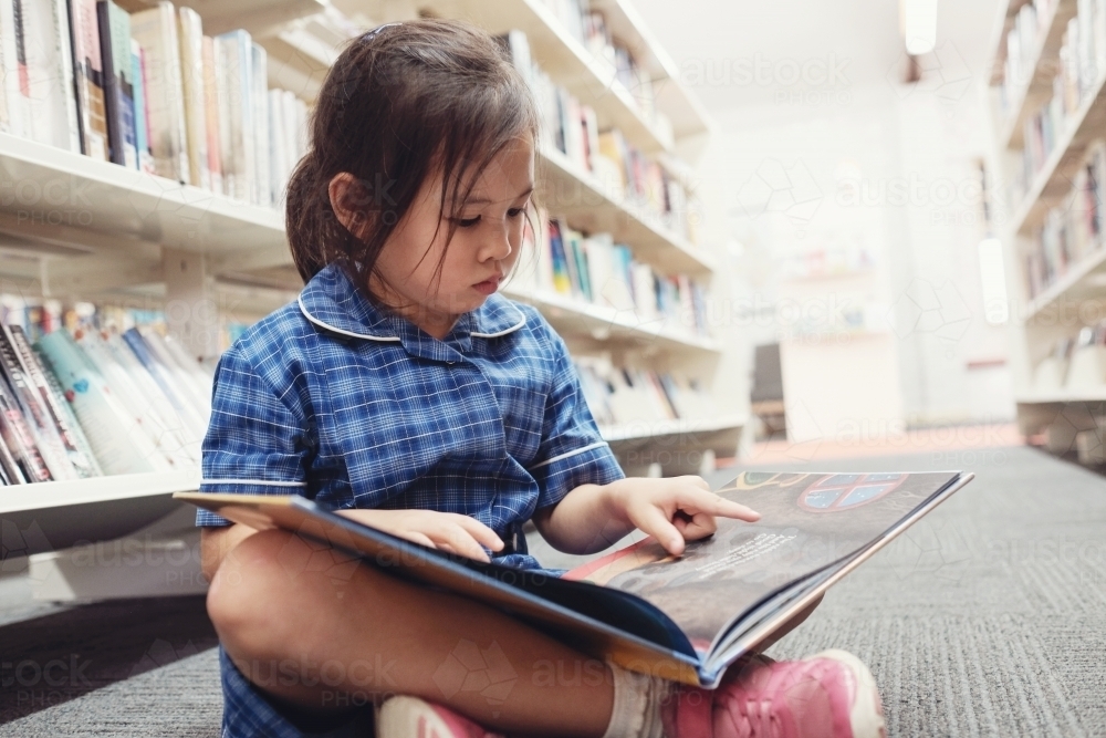 Young student girl reading in library - Australian Stock Image