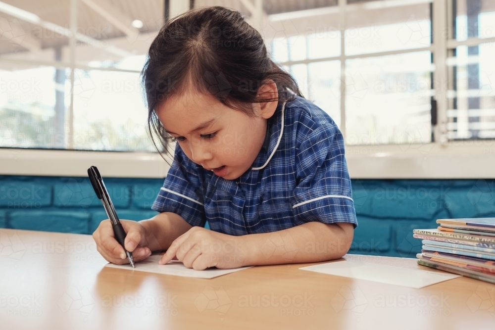 Young student girl writing in libary - Australian Stock Image