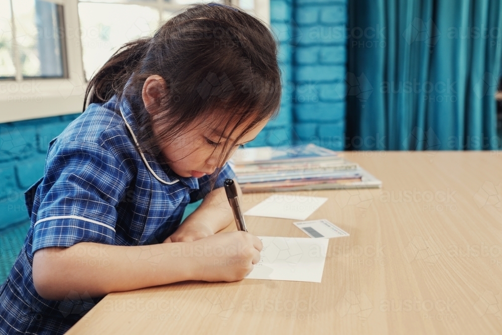 Young student girl writing in libary - Australian Stock Image